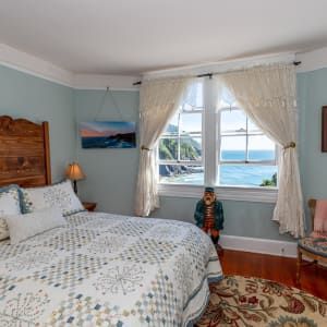 A bedroom with a bed , chair , window and rug.