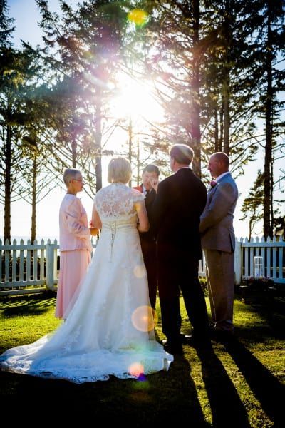 A group of people are standing around a bride and groom during a wedding ceremony.
