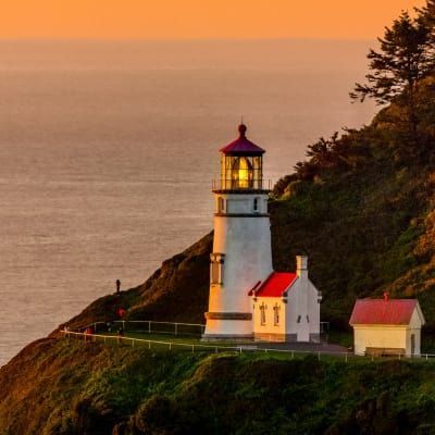 A lighthouse sits on top of a cliff overlooking the ocean