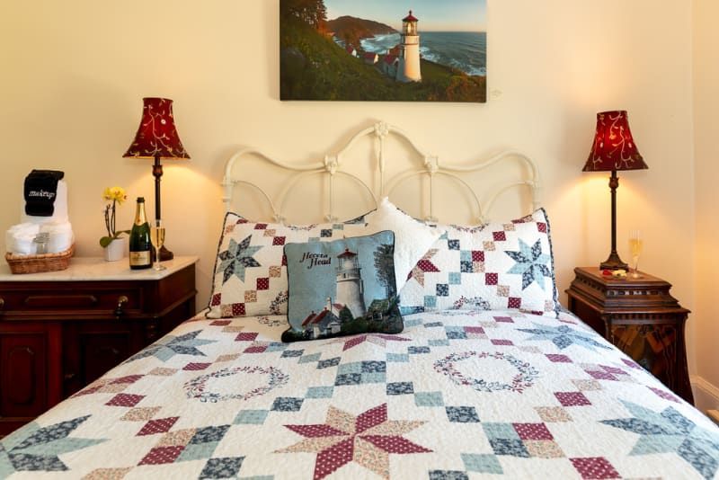 A bed with a quilt on it and a picture of a lighthouse on the wall above it