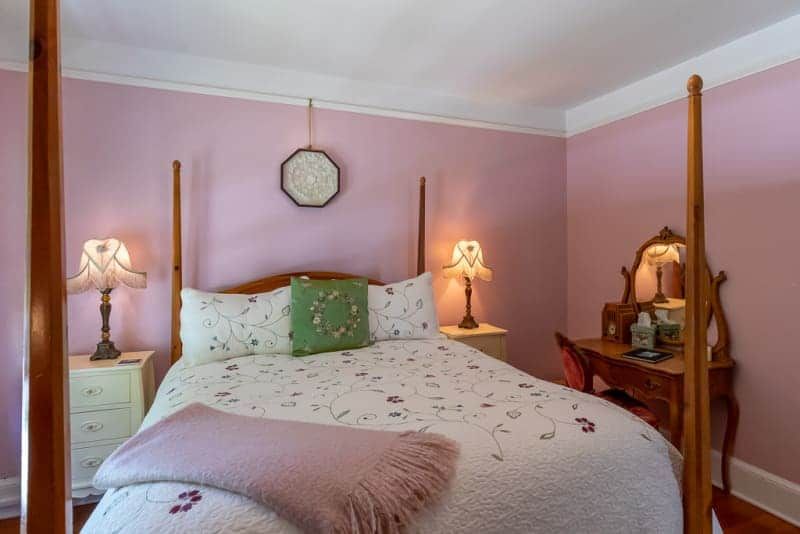 A bedroom with pink walls and a four poster bed.
