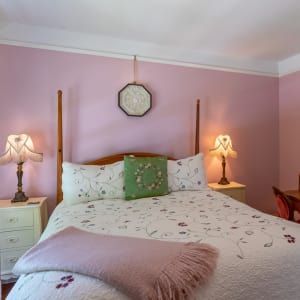 A bedroom with pink walls and a bed and two lamps
