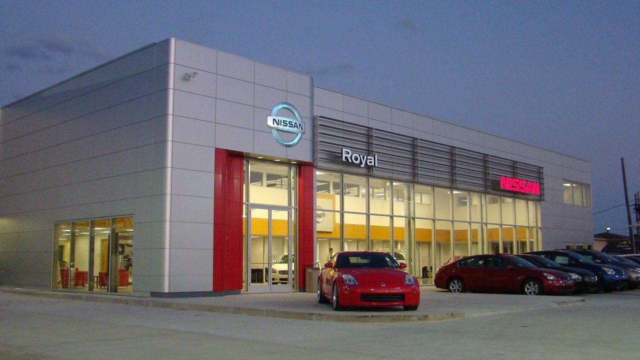Nissan dealership exterior with red and silver facade; cars on display.