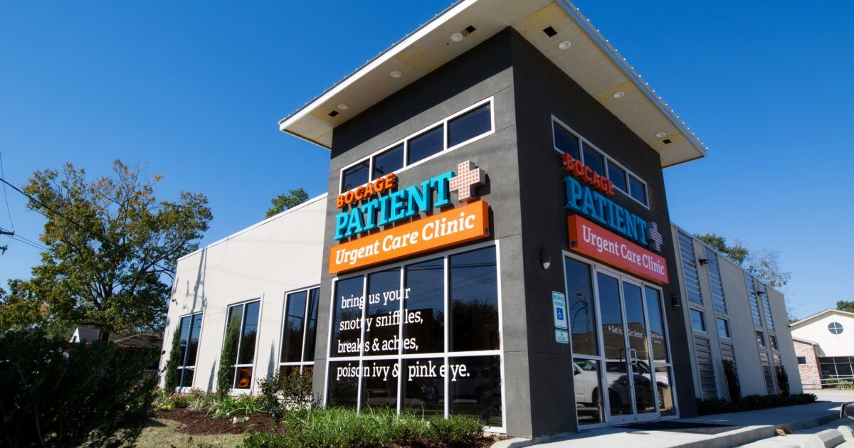 Exterior of an urgent care clinic; gray and white building with large windows and a blue sky.