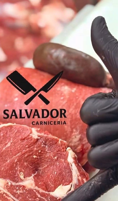 Una persona que lleva guantes negros sostiene un trozo de carne y hace un gesto de pulgar hacia arriba.