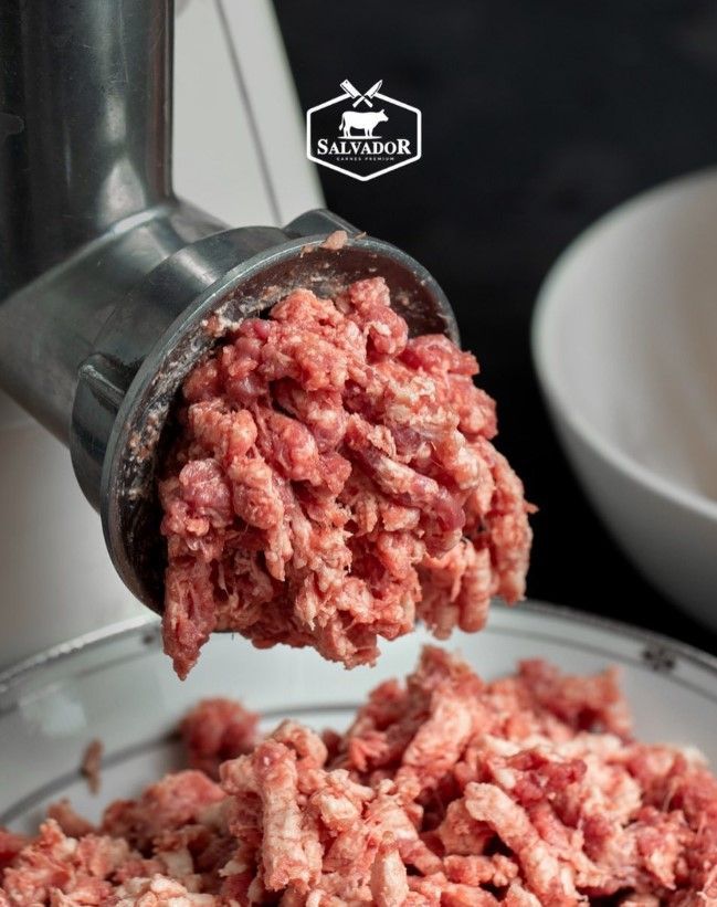 A close up of a meat grinder filled with ground meat