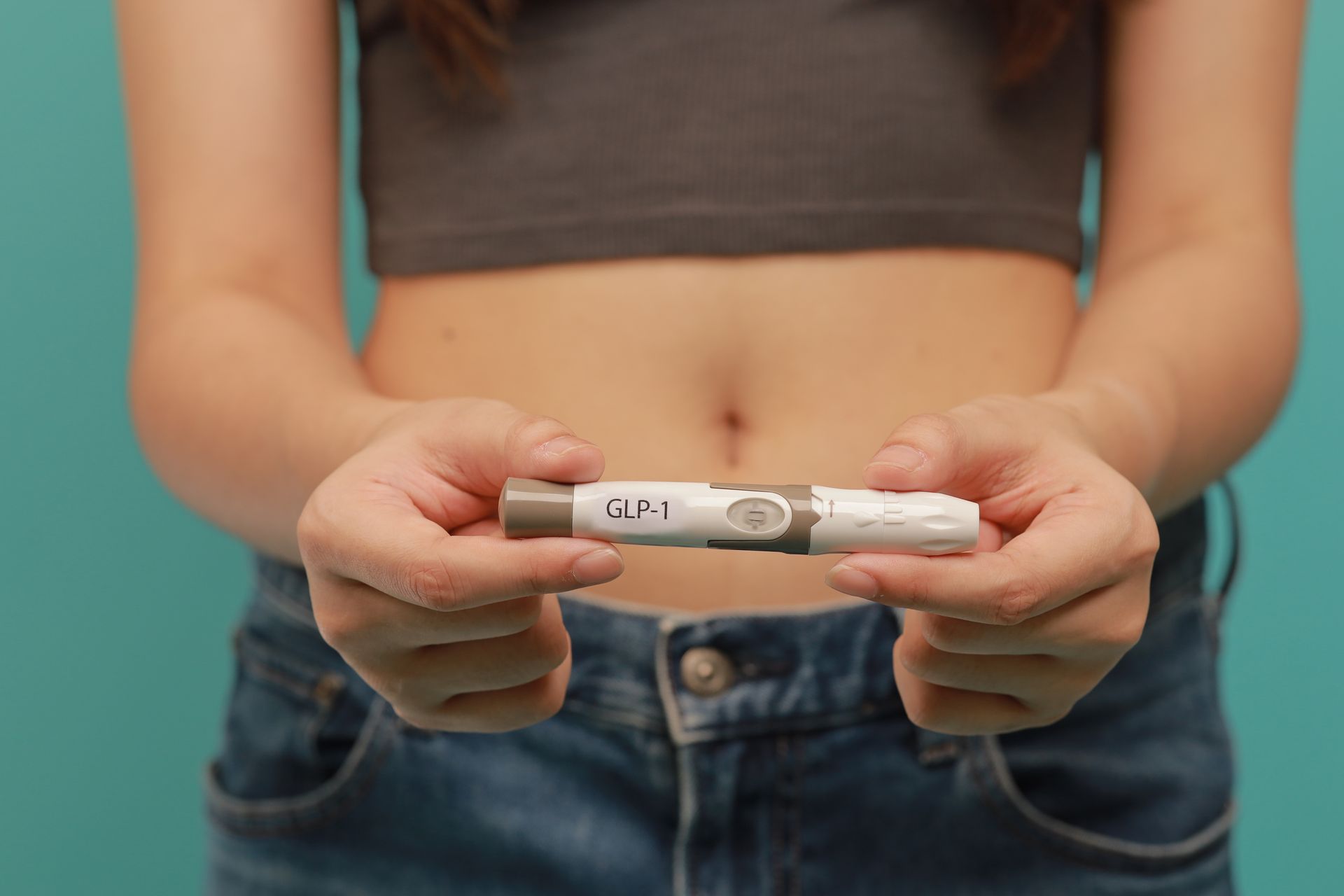 Hands holding a white glucose meter over a bare midriff, suggesting a diabetes check