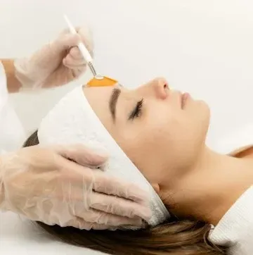 RN at studio med spa applying chemical peel solution on client's forehead