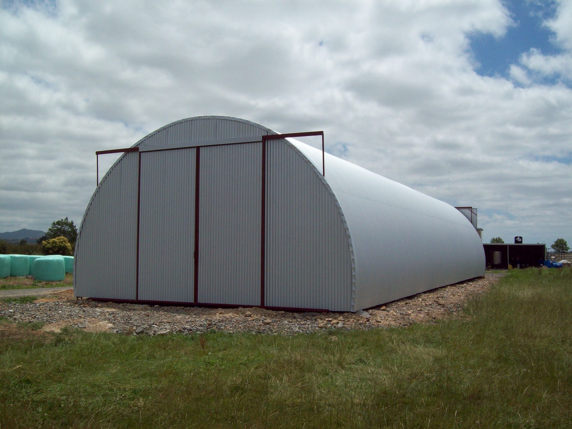 A large white building is sitting in the middle of a field.