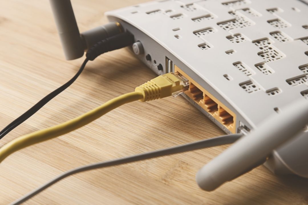 A Router is Sitting on a Wooden Table With a Yellow Cable Plugged Into It — Lismore Computer Solutions in Alstonville, NSW
