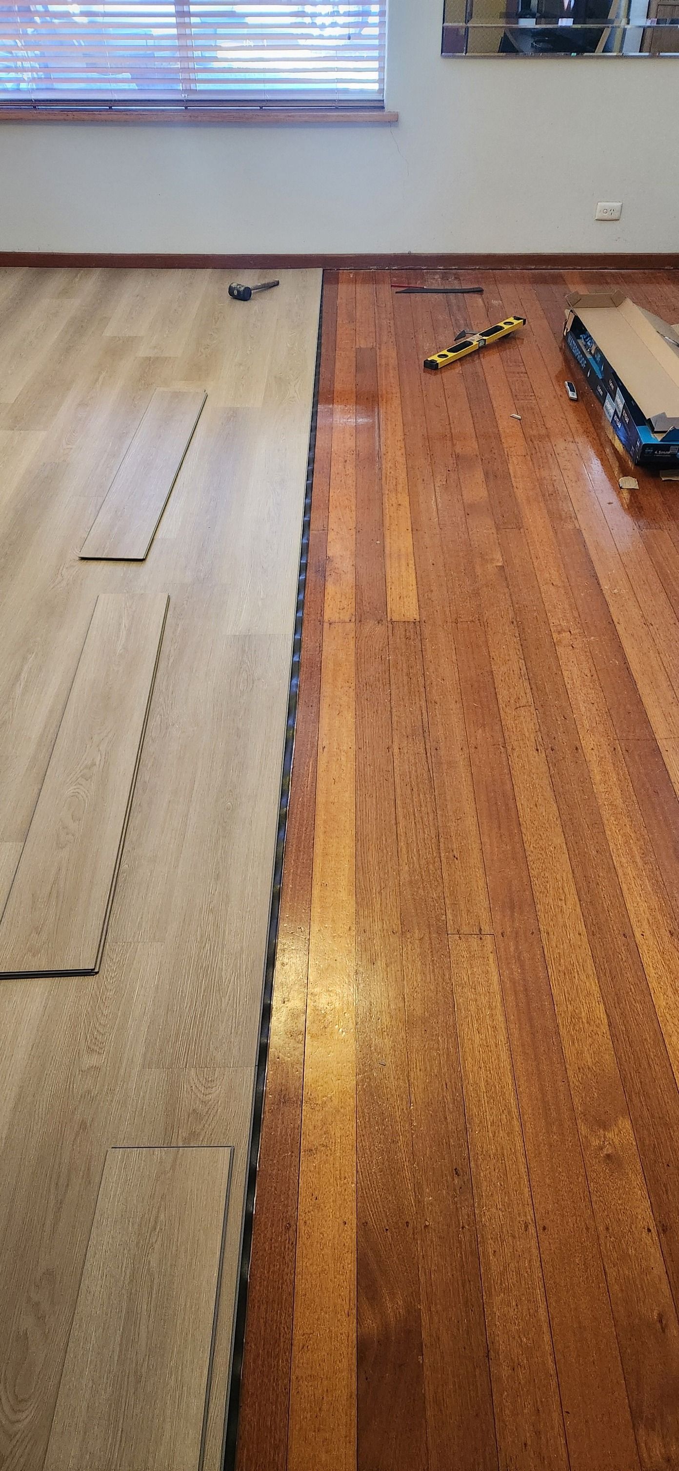 Floor installation: Light wood floor next to dark wood floor. Blinds in the background — Carro's Property Maintenance in Kaleen, ACT