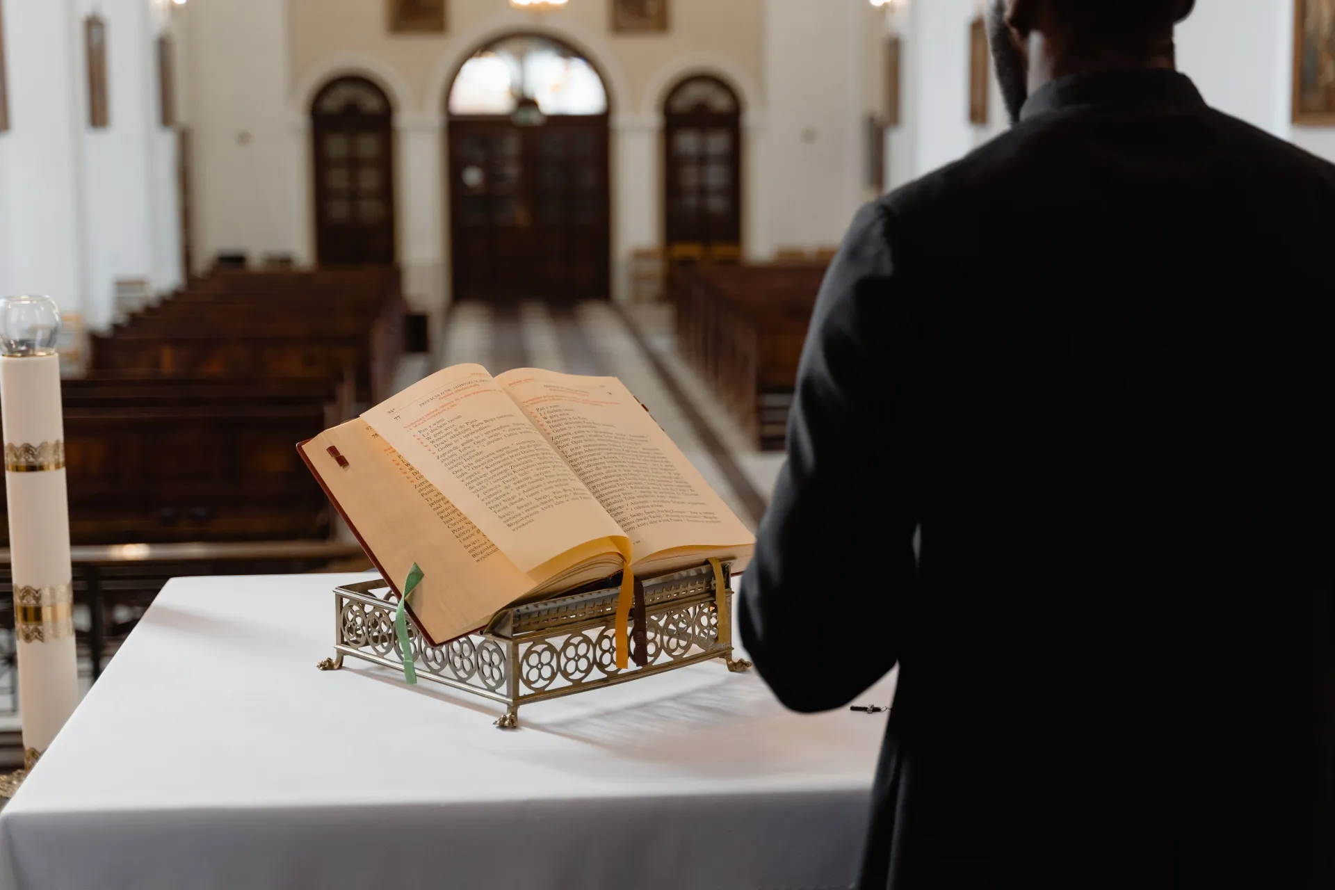A man is standing in front of an open bible in a church.