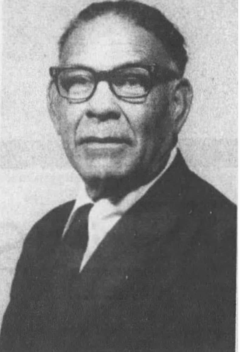 Man in glasses and suit, looking towards the viewer, studio portrait.