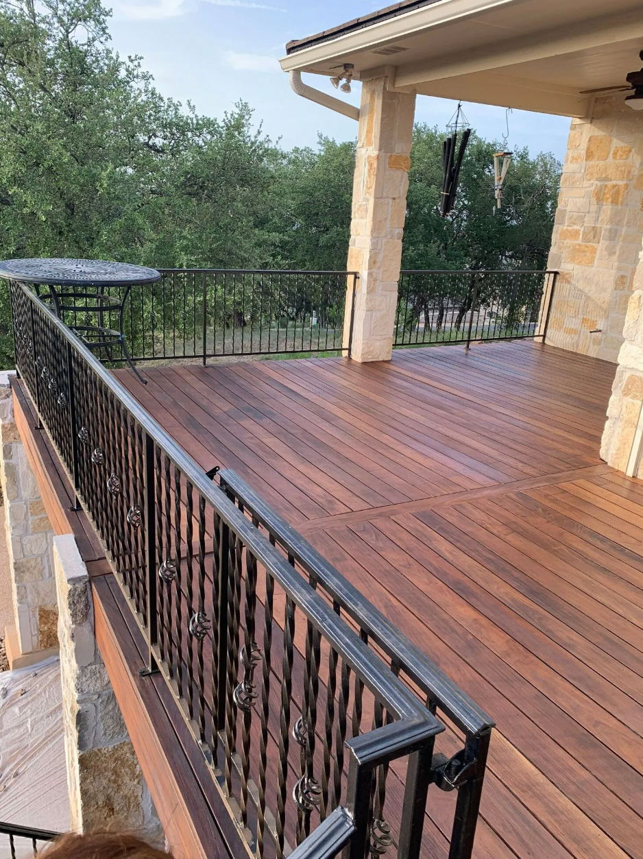 A wooden deck with a wrought iron railing and a table on it.