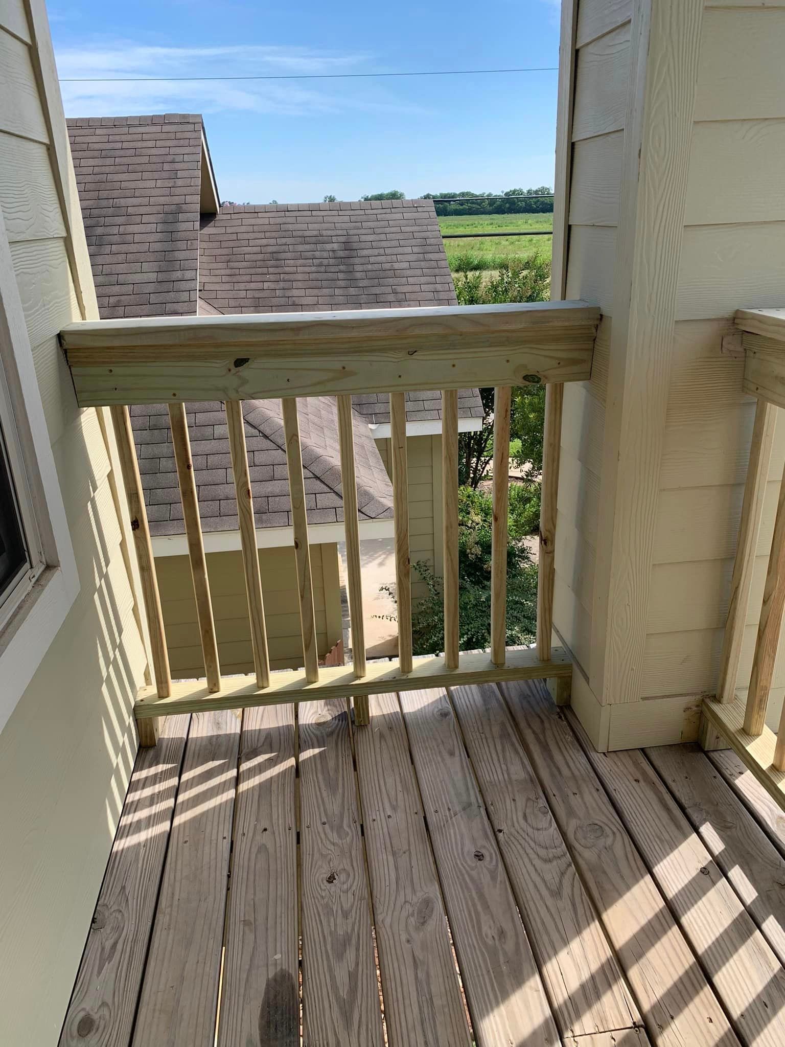 A balcony with a wooden railing and a view of a house.