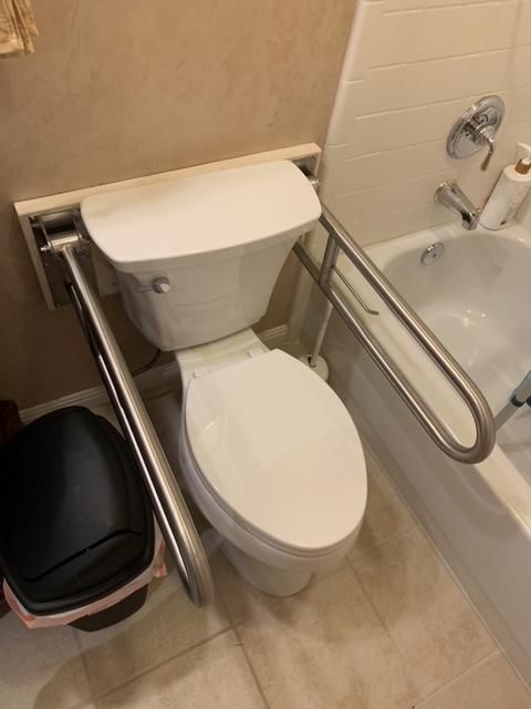 A bathroom with a toilet , trash can , and bathtub.