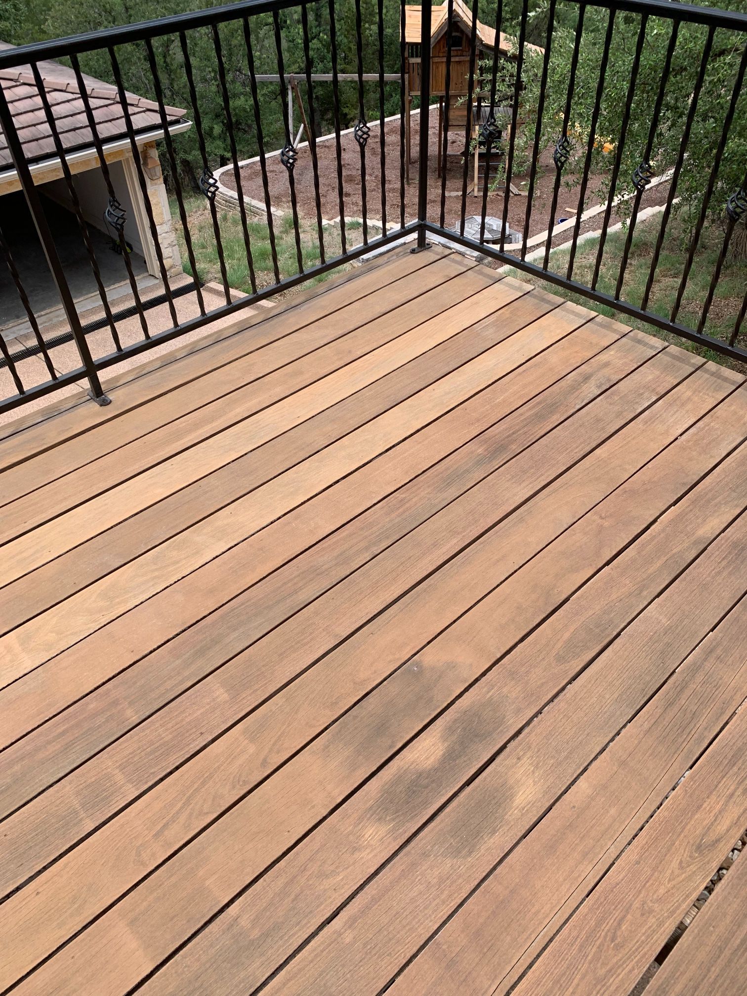 A wooden deck with a metal railing and a view of a playground.