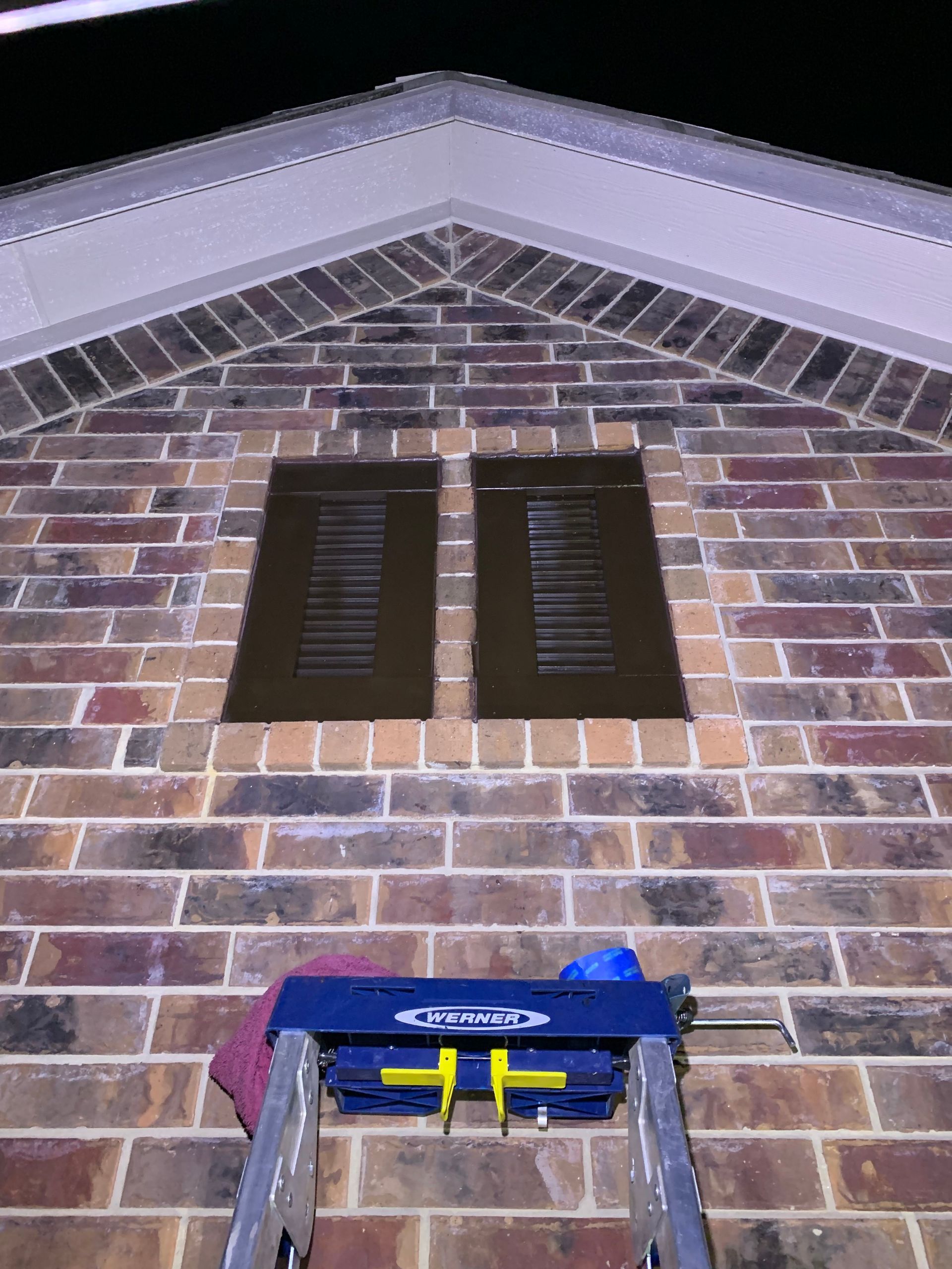 A ladder is sitting on the side of a brick building.