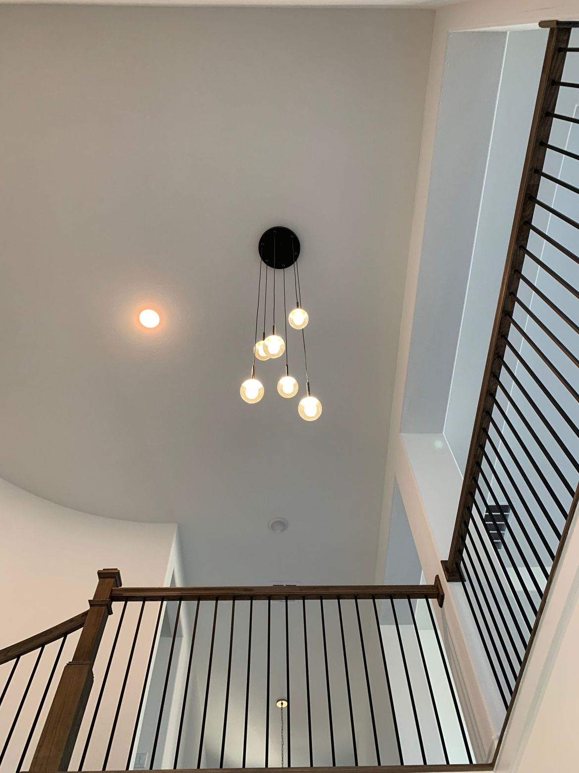 Looking up at a staircase with a chandelier hanging from the ceiling.