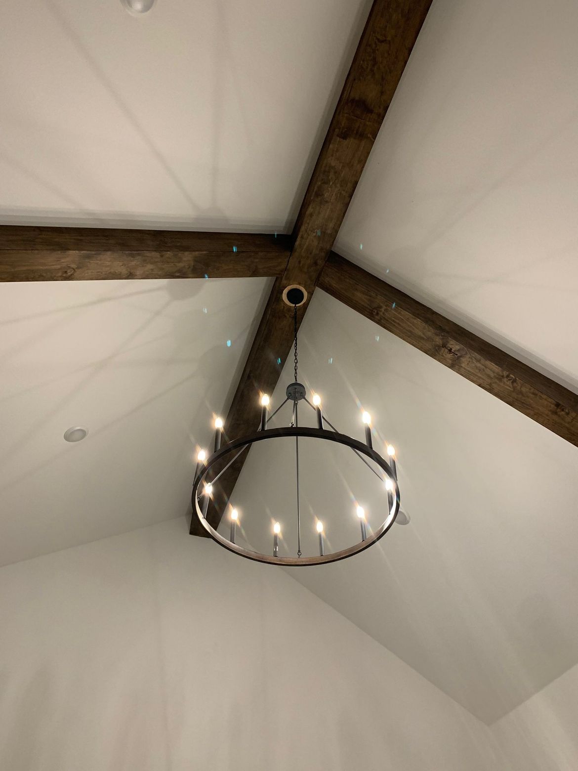 A chandelier is hanging from the ceiling of a room with wooden beams.