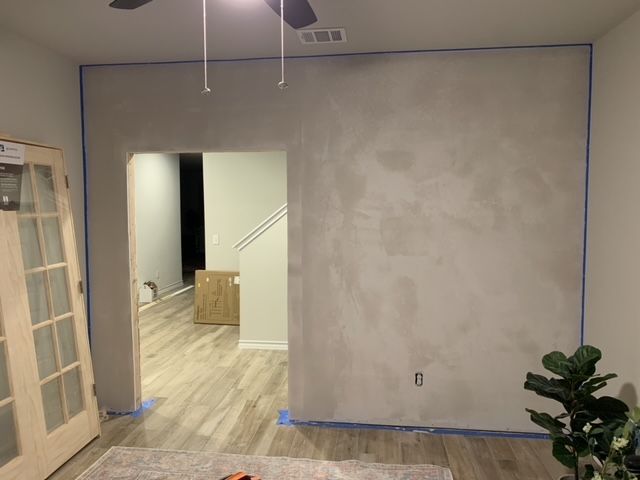 A living room with a white wall and a ceiling fan.