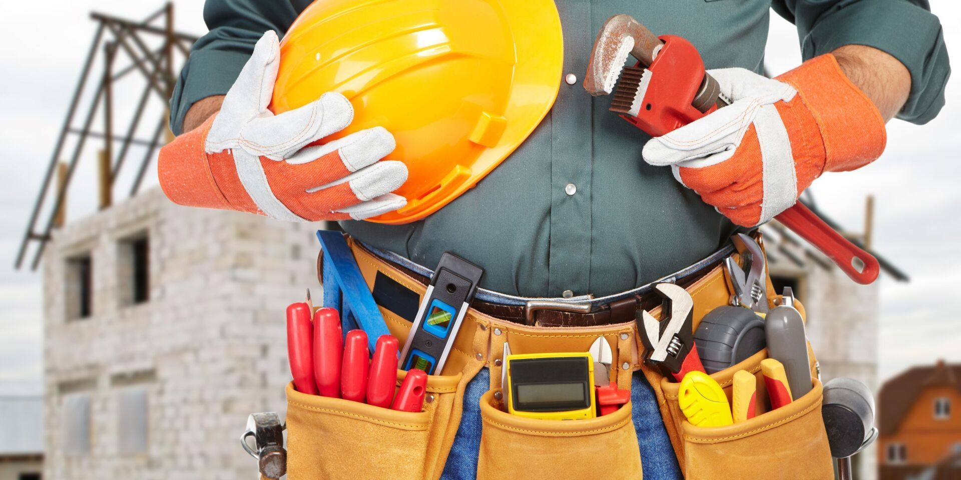 A construction worker is holding a hard hat and a wrench.