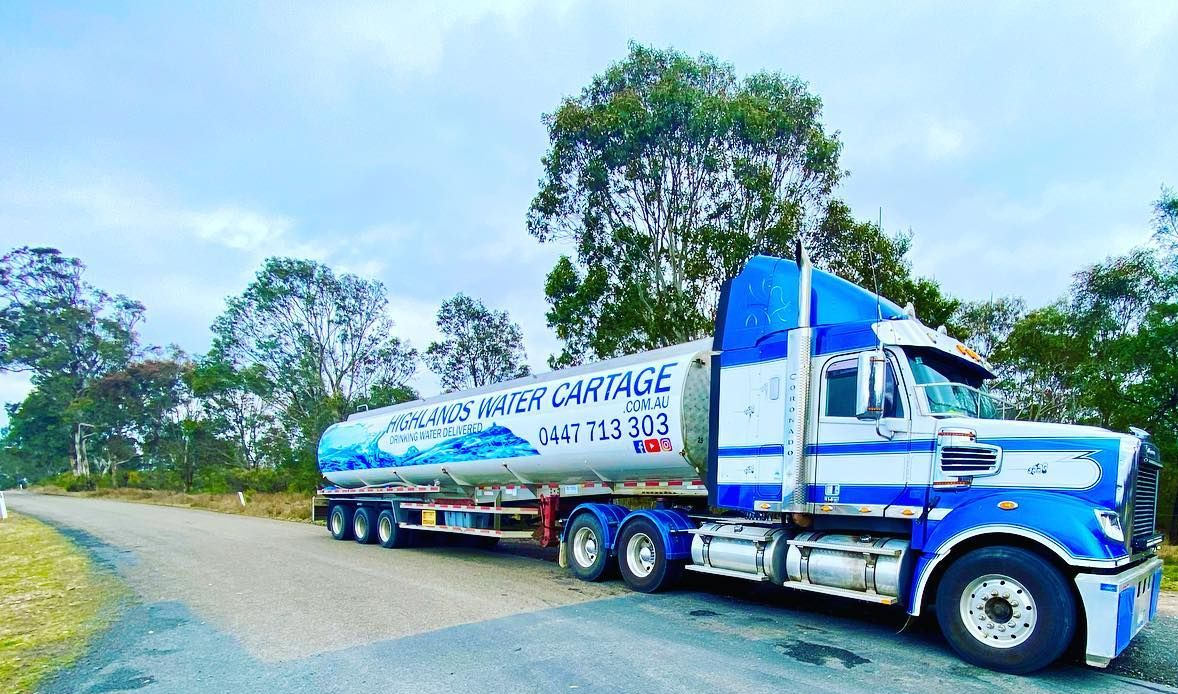 Blue and white water tanker truck parked on a road, with trees and a cloudy sky — Highlands Water Cartage in Glenquarry, NSW