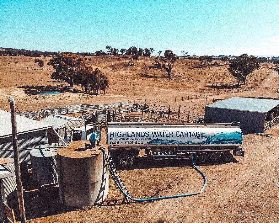 Water tanker filling storage tanks on a dry, rural property — Highlands Water Cartage in Glenquarry, NSW