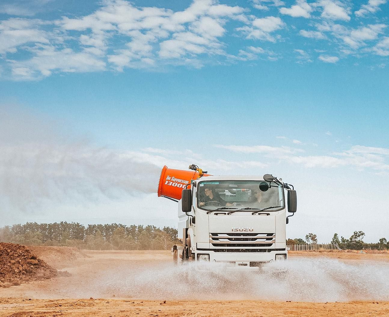 Truck spraying water on dirt road under a blue sky — Highlands Water Cartage in Glenquarry, NSW