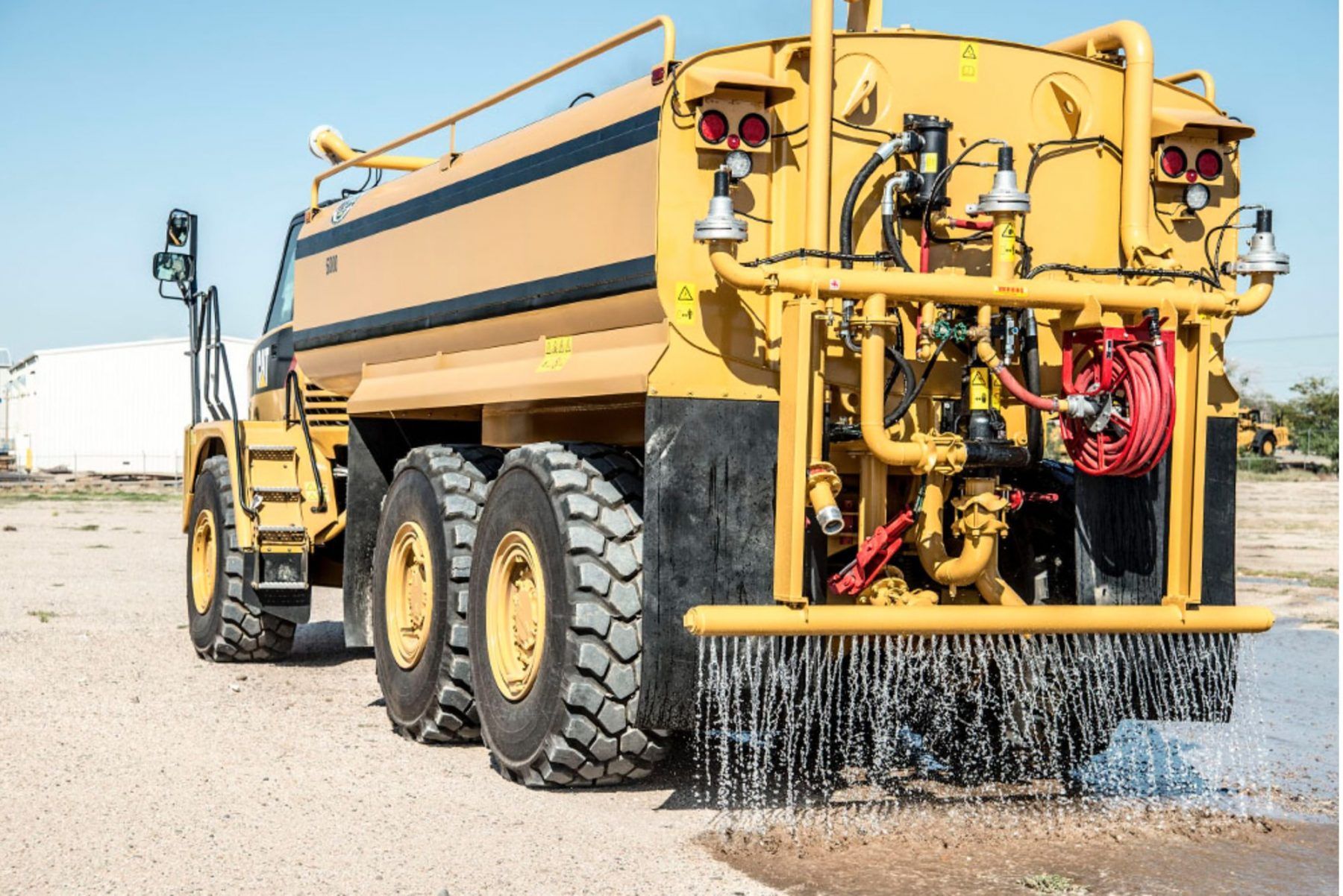 Yellow water truck spraying water on a gravel road — Highlands Water Cartage in Glenquarry, NSW