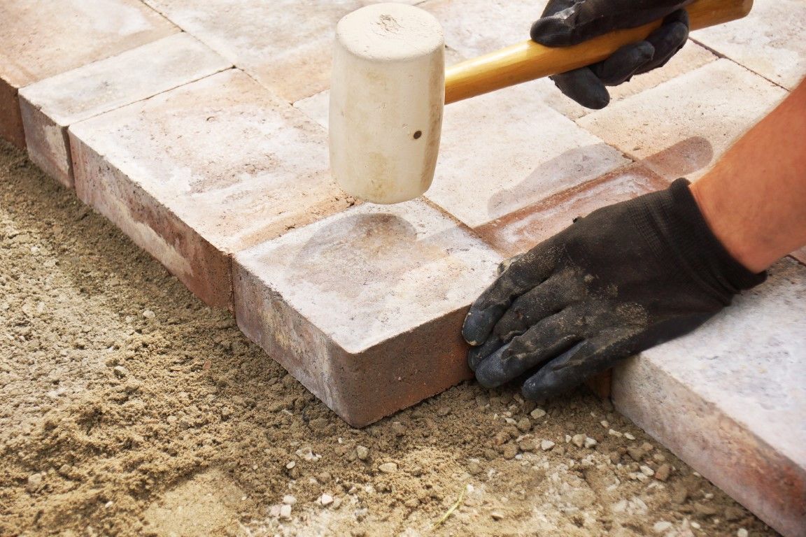 Photo of installer compacting pavers with mallet during paver installation 