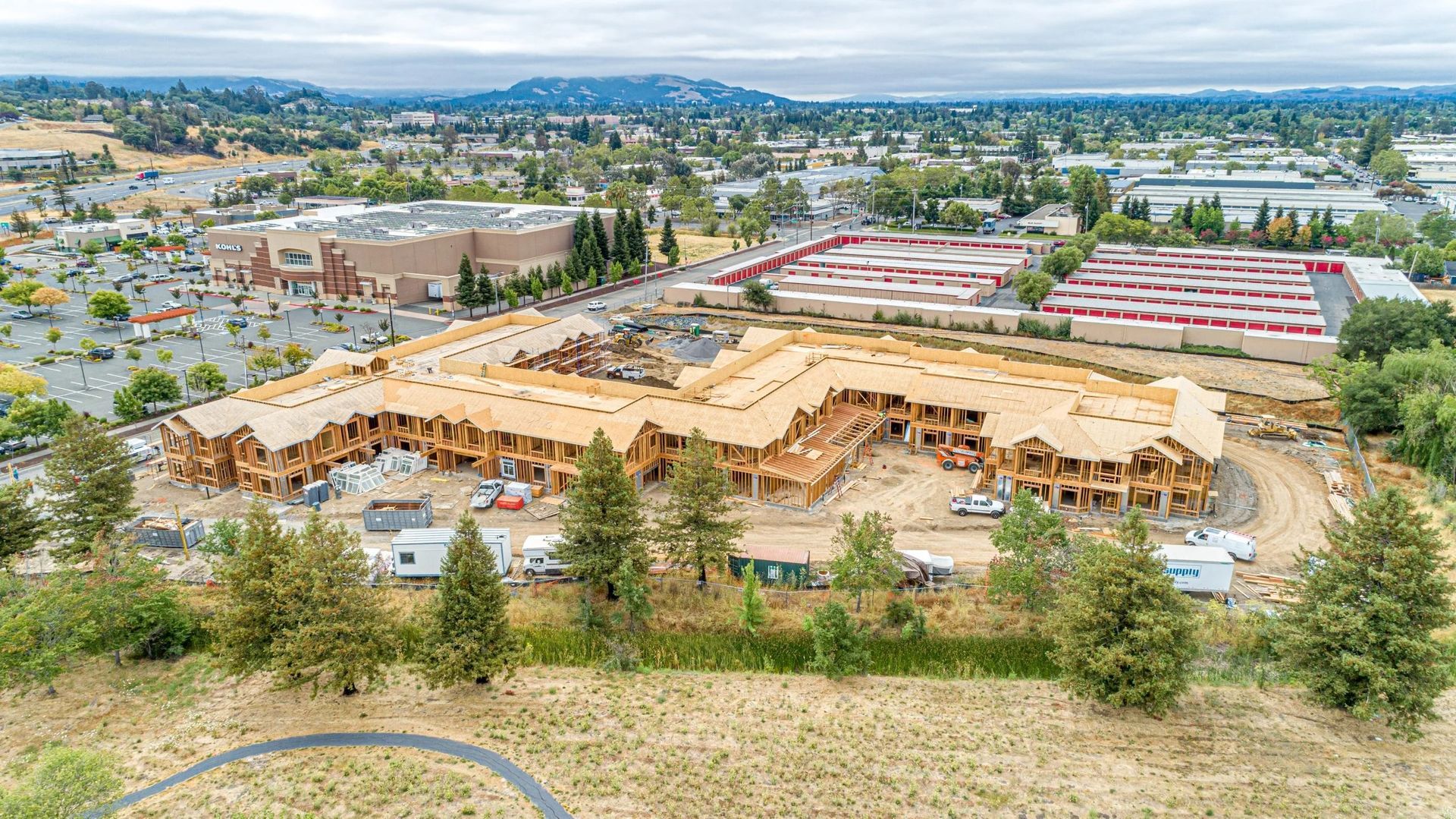 Aerial view of a large beige-roofed apartment complex under construction in a suburban area.