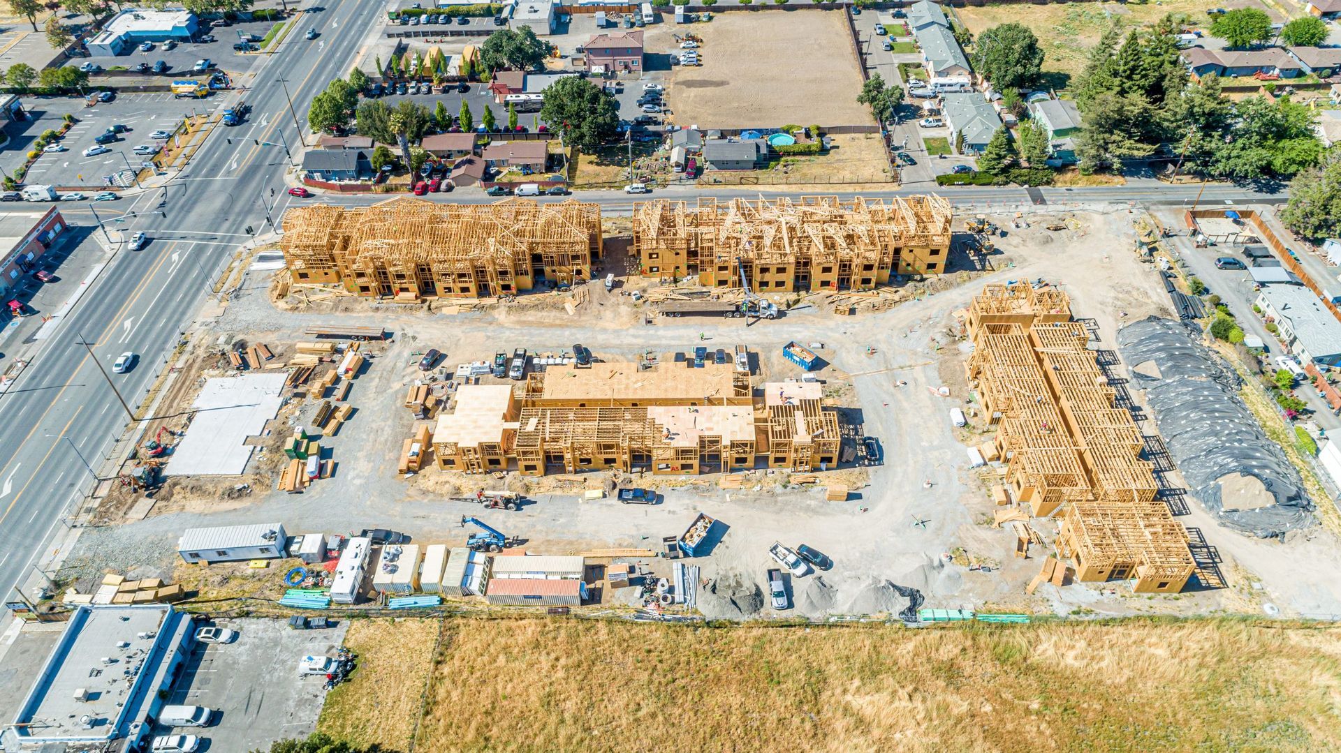 Aerial view of a residential construction site featuring multiple wood-framed building structures in progress.