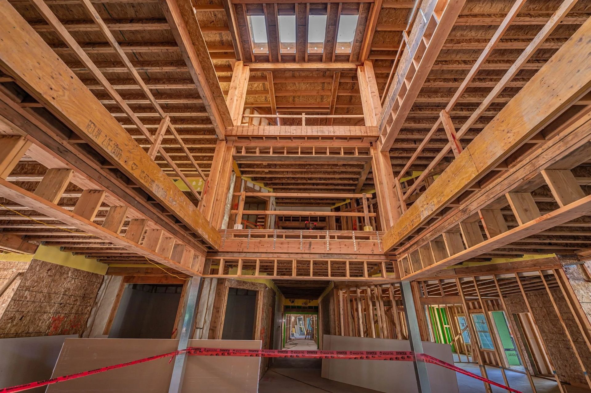 Interior view of a wood-framed building under construction with a multi-level open atrium and exposed floor joists.