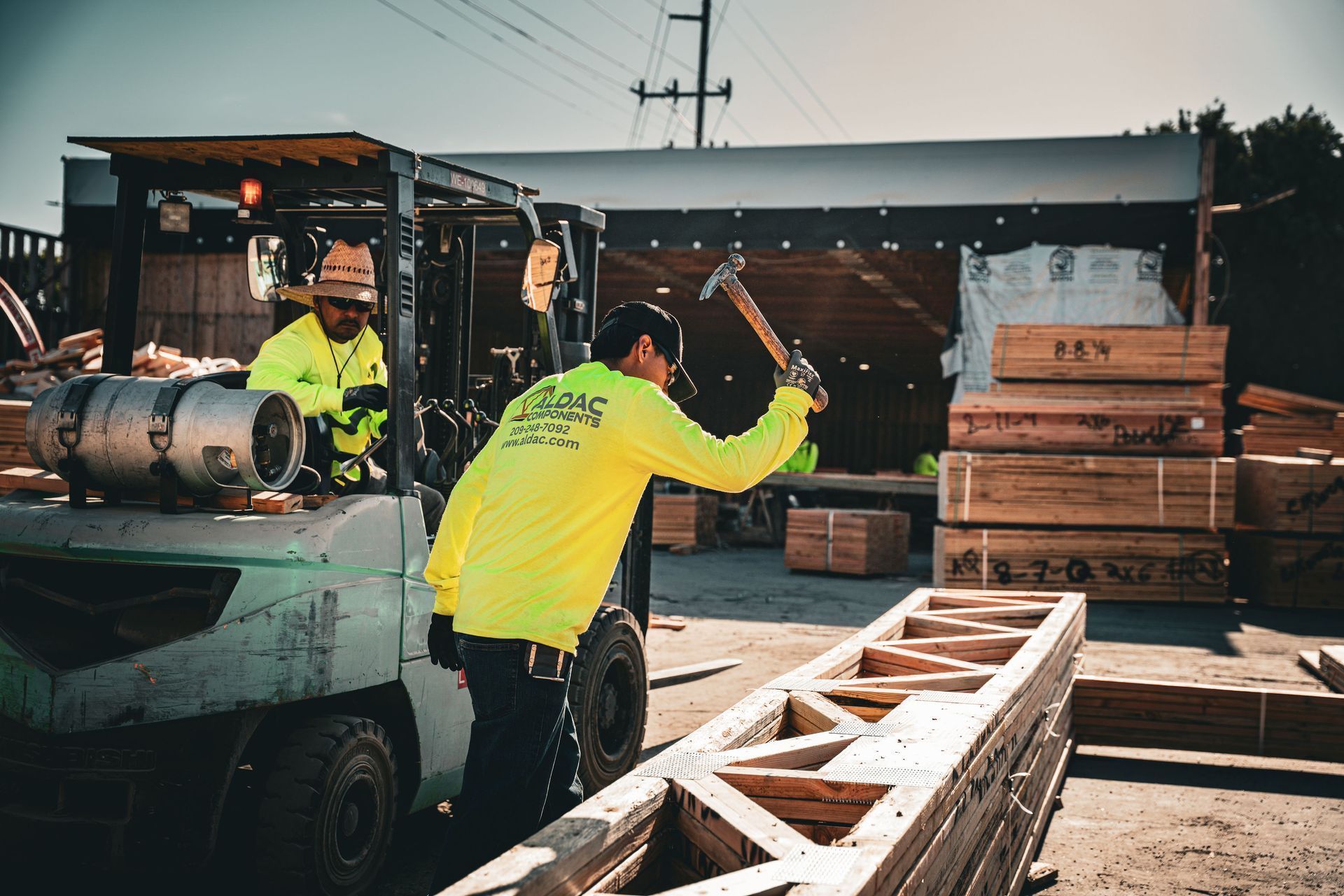Workers in neon jackets loading lumber onto a flatbed truck at a construction site