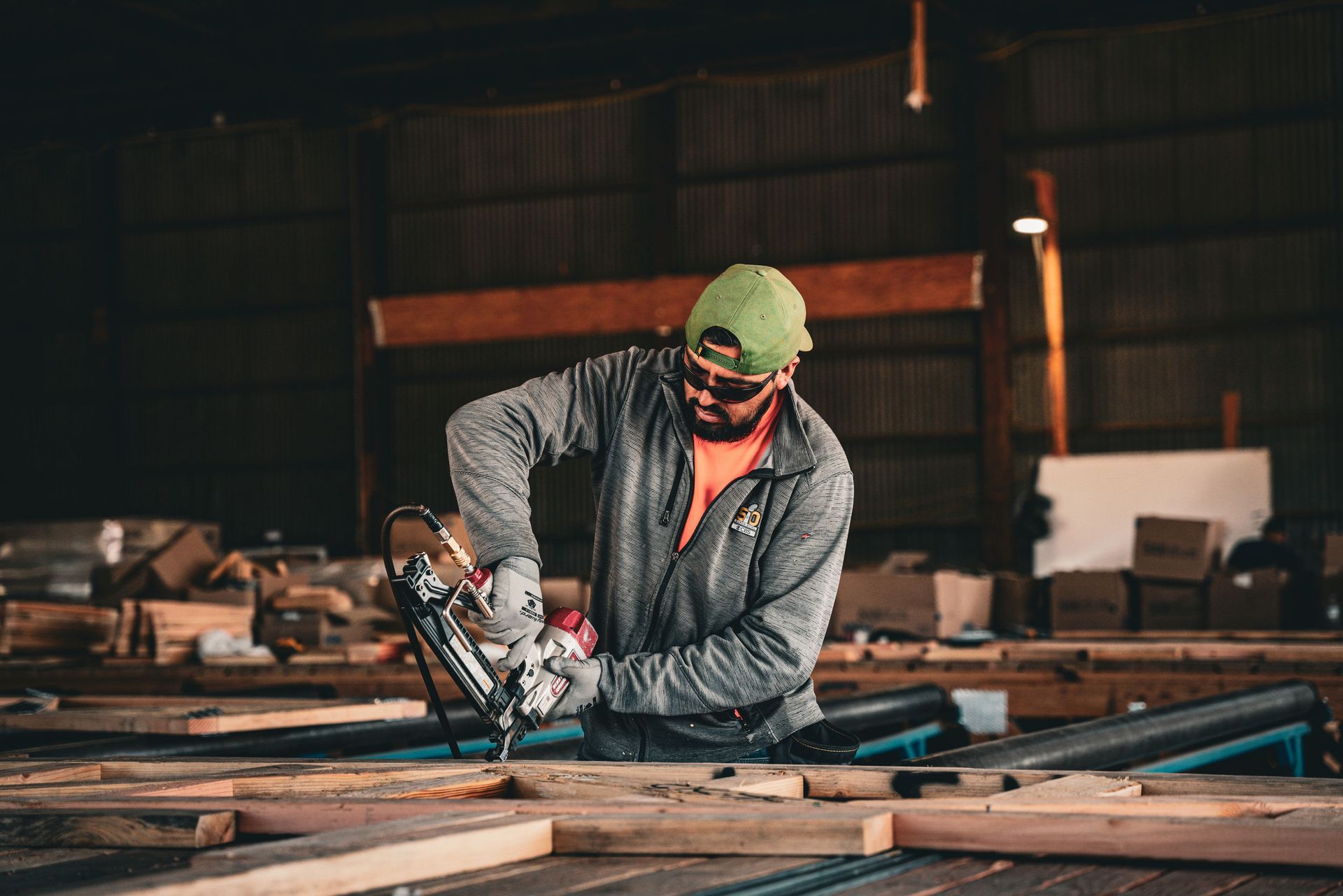 Worker cutting wood with a circular saw in a dim workshop