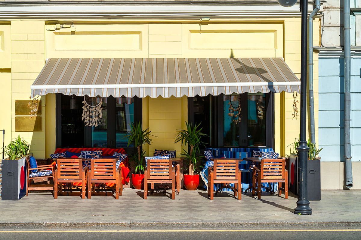 A commercial shopfront featuring a striped fabric awning from a professional sunshade awning manufa