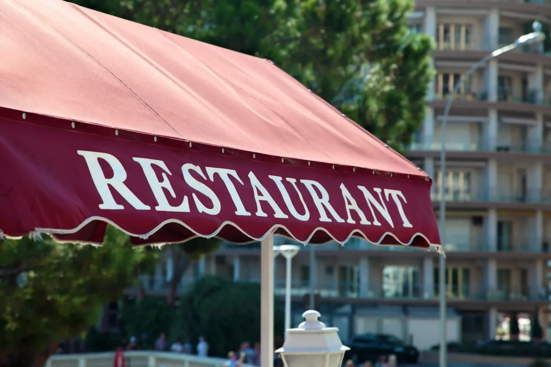 A red restaurant shoplot awning with white lettering over an outdoor commercial storefront.