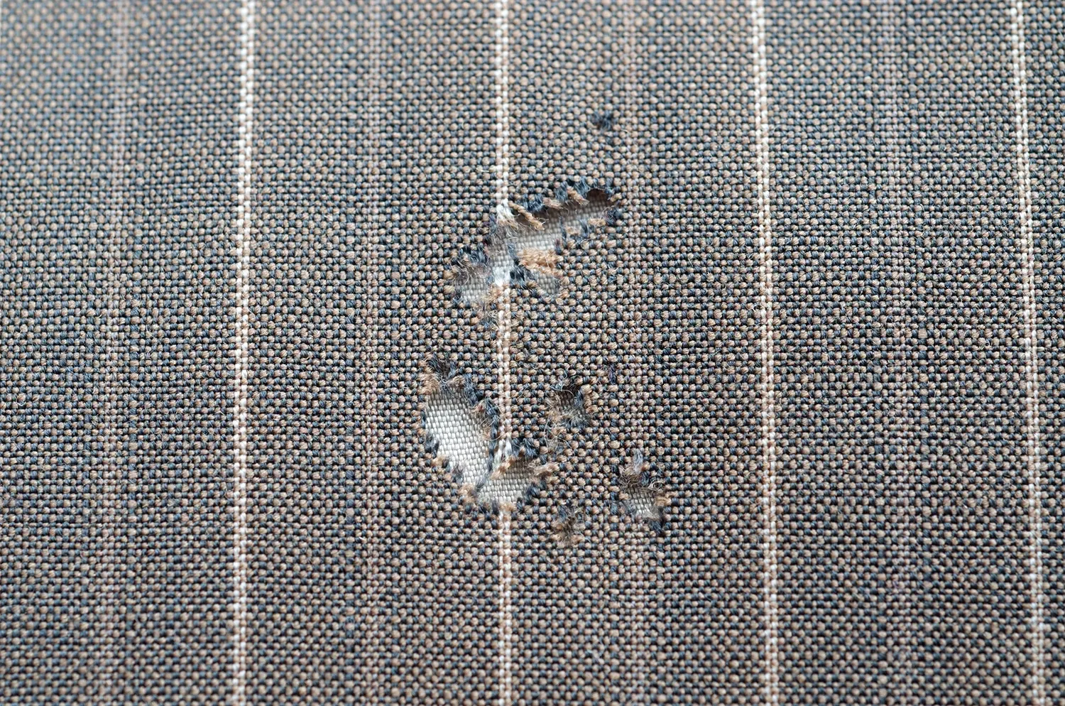 Close-up of torn striped fabric showing frayed edges in need of awning fabric repair.