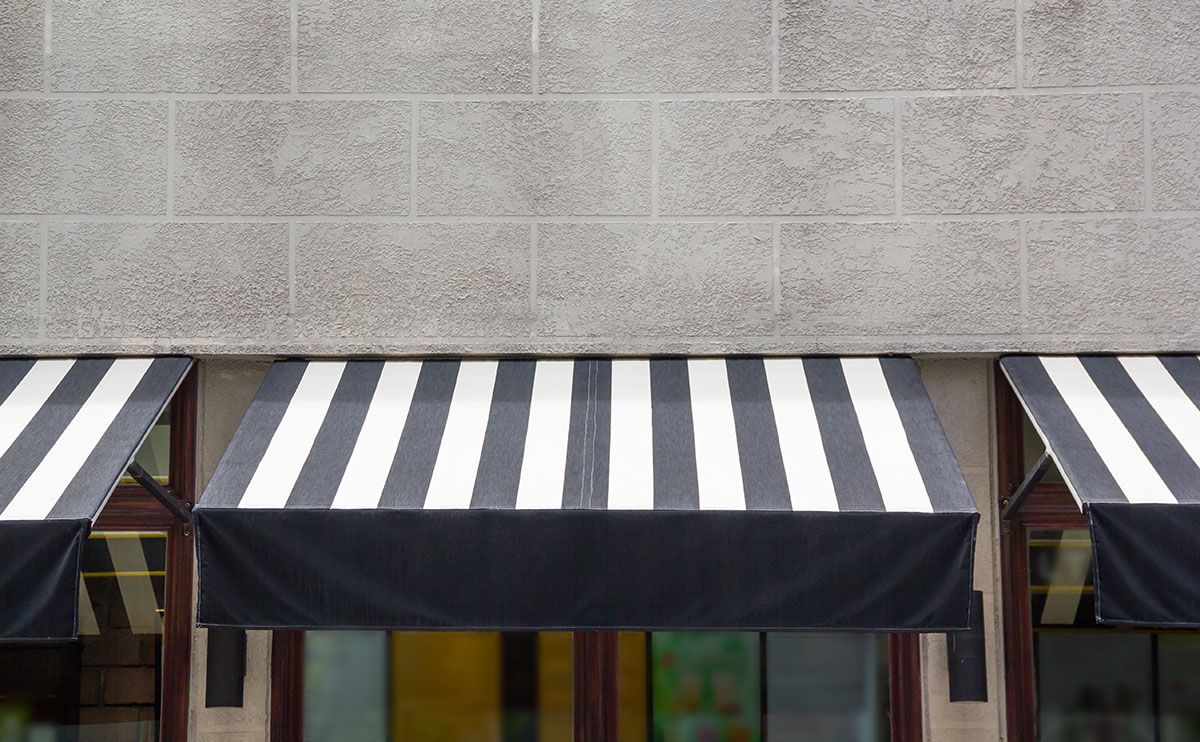 Fixed black and white striped awnings, designed by a professional fixed awning manufacturer