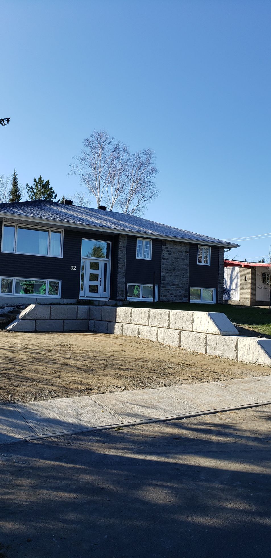 Une grande maison avec beaucoup de fenêtres est située au sommet d'un champ de terre.