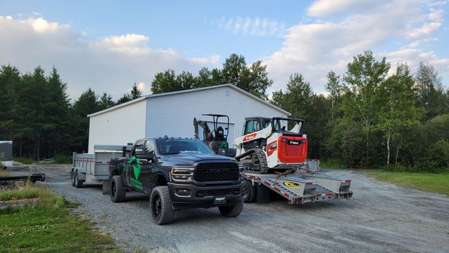 Un camion tire une remorque avec un bulldozer dessus.