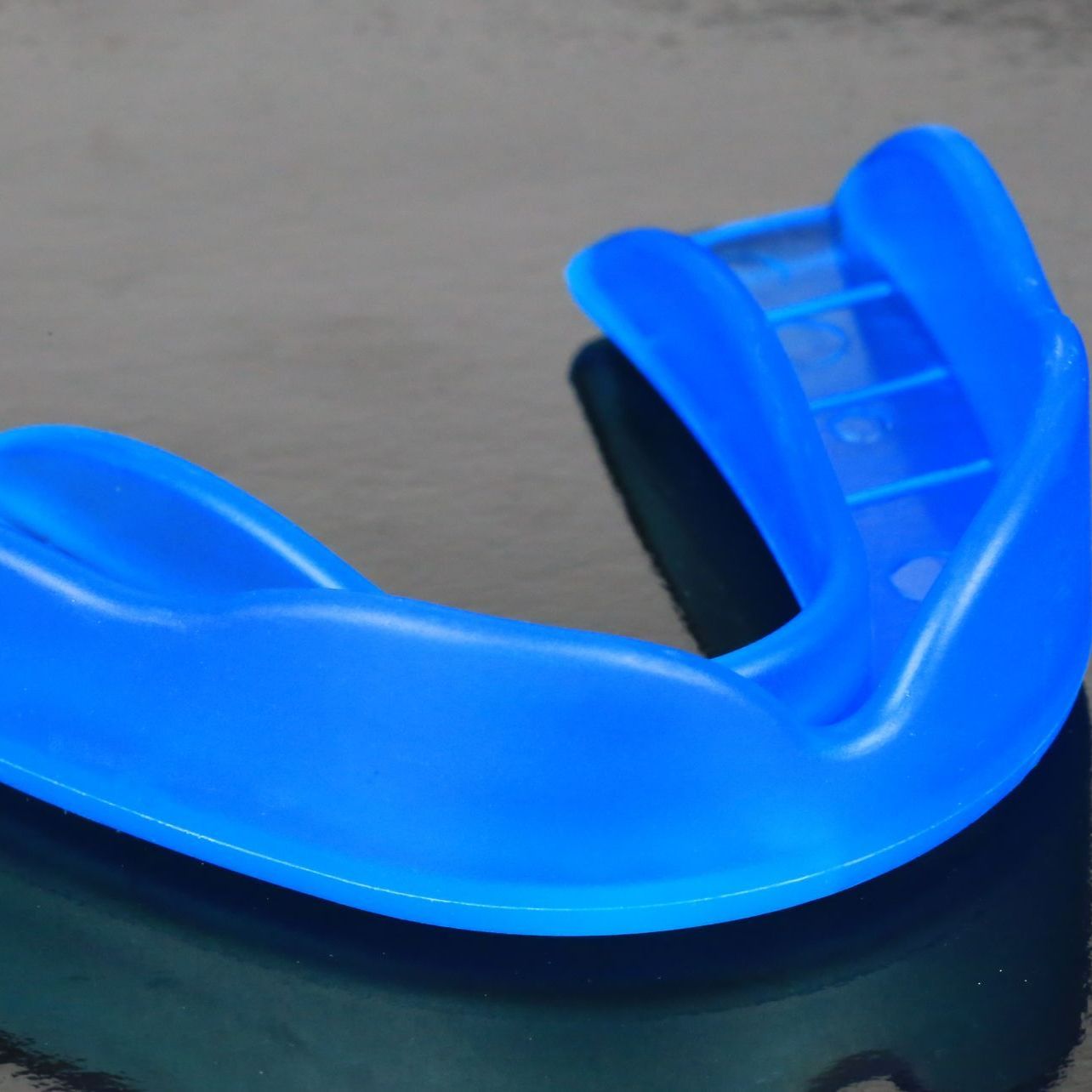 Blue mouthguard on a reflective surface.