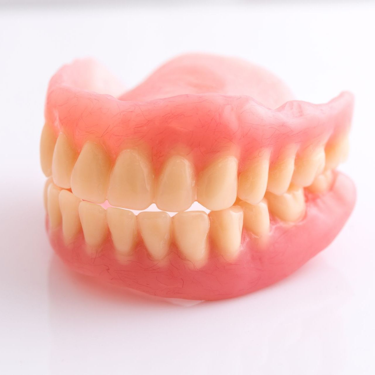 Dentures on a white surface, showing upper and lower sets of artificial teeth.