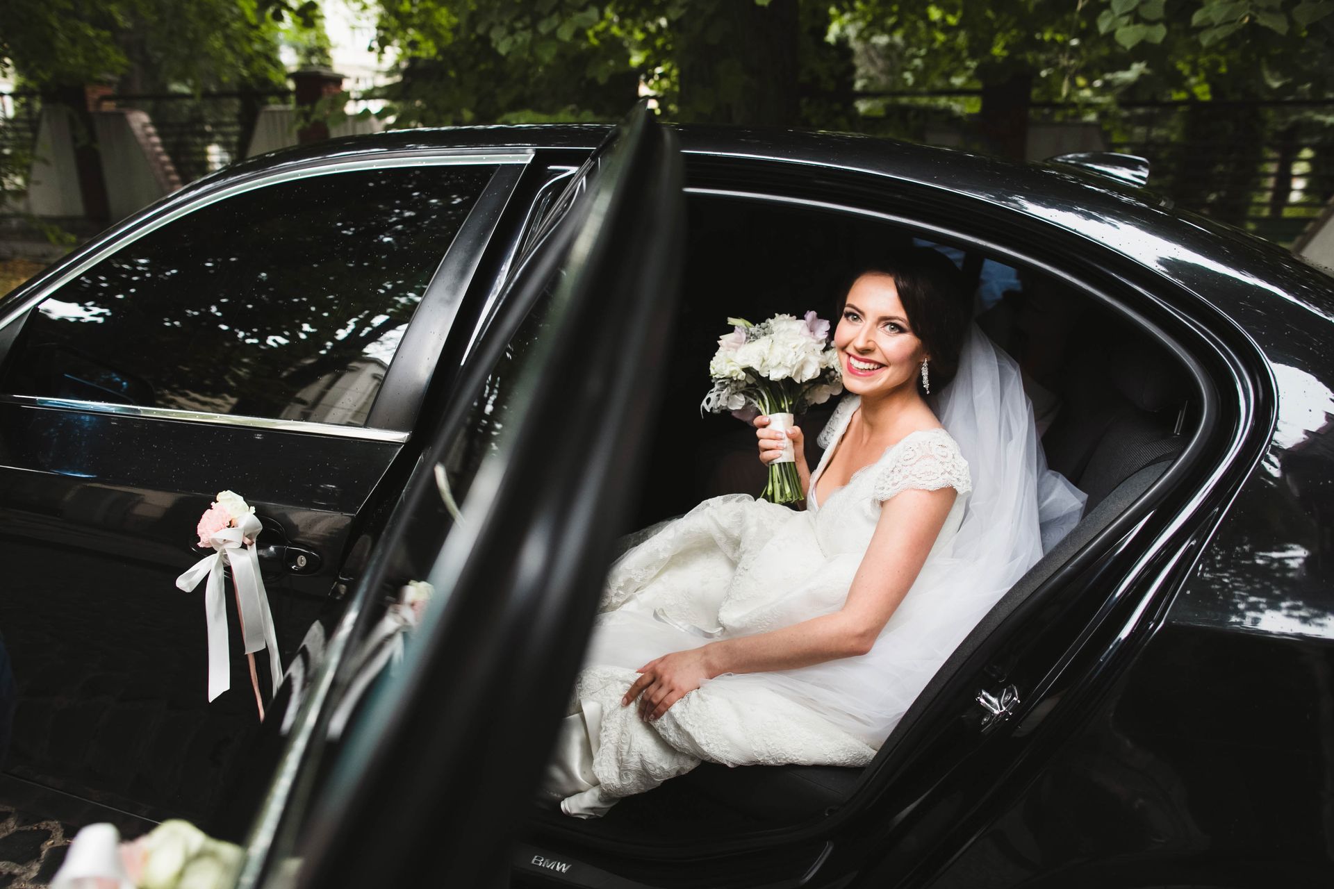 Happy bride with bouquet in a black car, the perfect stair wedding transportation choice. Happy bride with bouquet in a black car, the perfect stair wedding transportation choice.