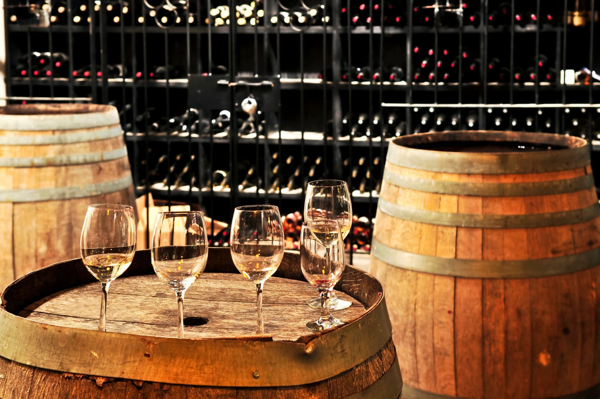 Wine glasses on wooden barrels in a dimly lit wine cellar