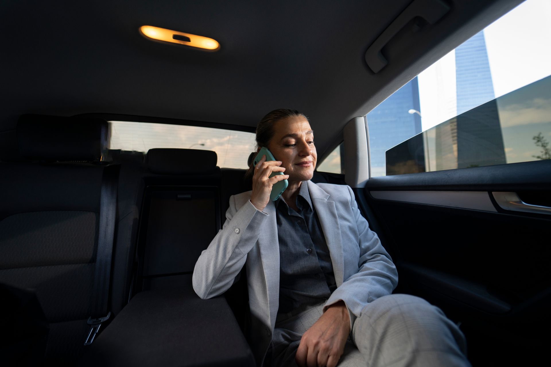 Man in a dark suit sitting in a limousine, talking on a phone by the window