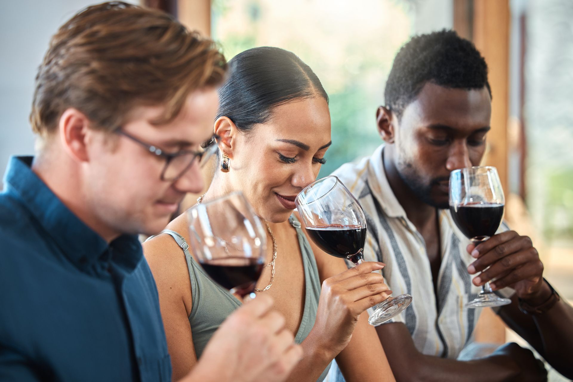 A diverse group of three people, two men and one woman, taste wine with a cup each. A diverse group of three people, two men and one woman, taste wine with a cup each.