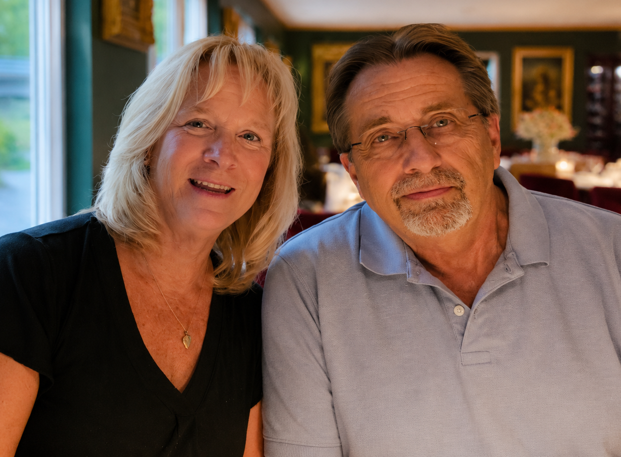 Two people smiling indoors, seated close together in a warmly lit room. Two people smiling indoors, seated close together in a warmly lit room.