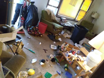 A messy living room with a vacuum cleaner on the floor